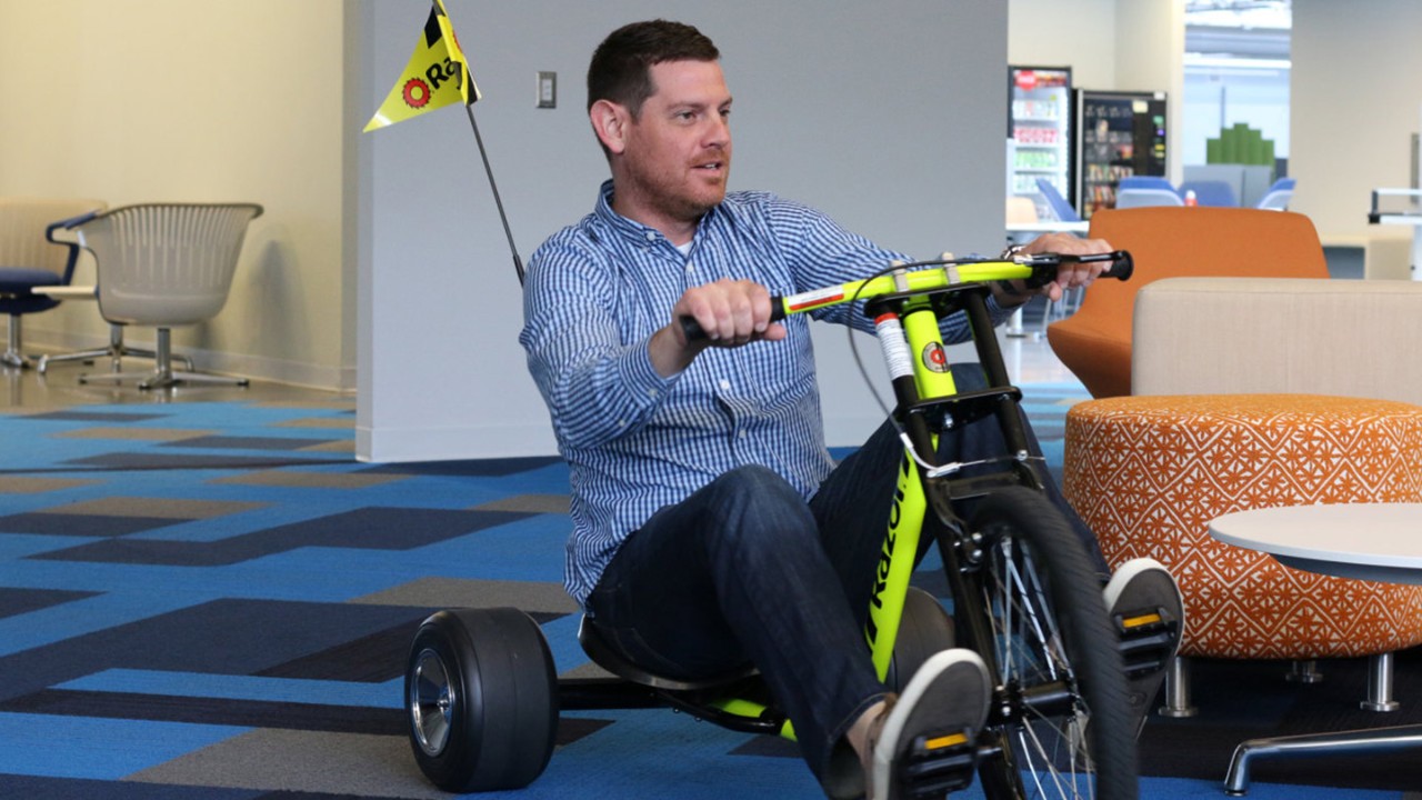 Booz Allen employee in Charleston, SC, office riding a car he built with the team