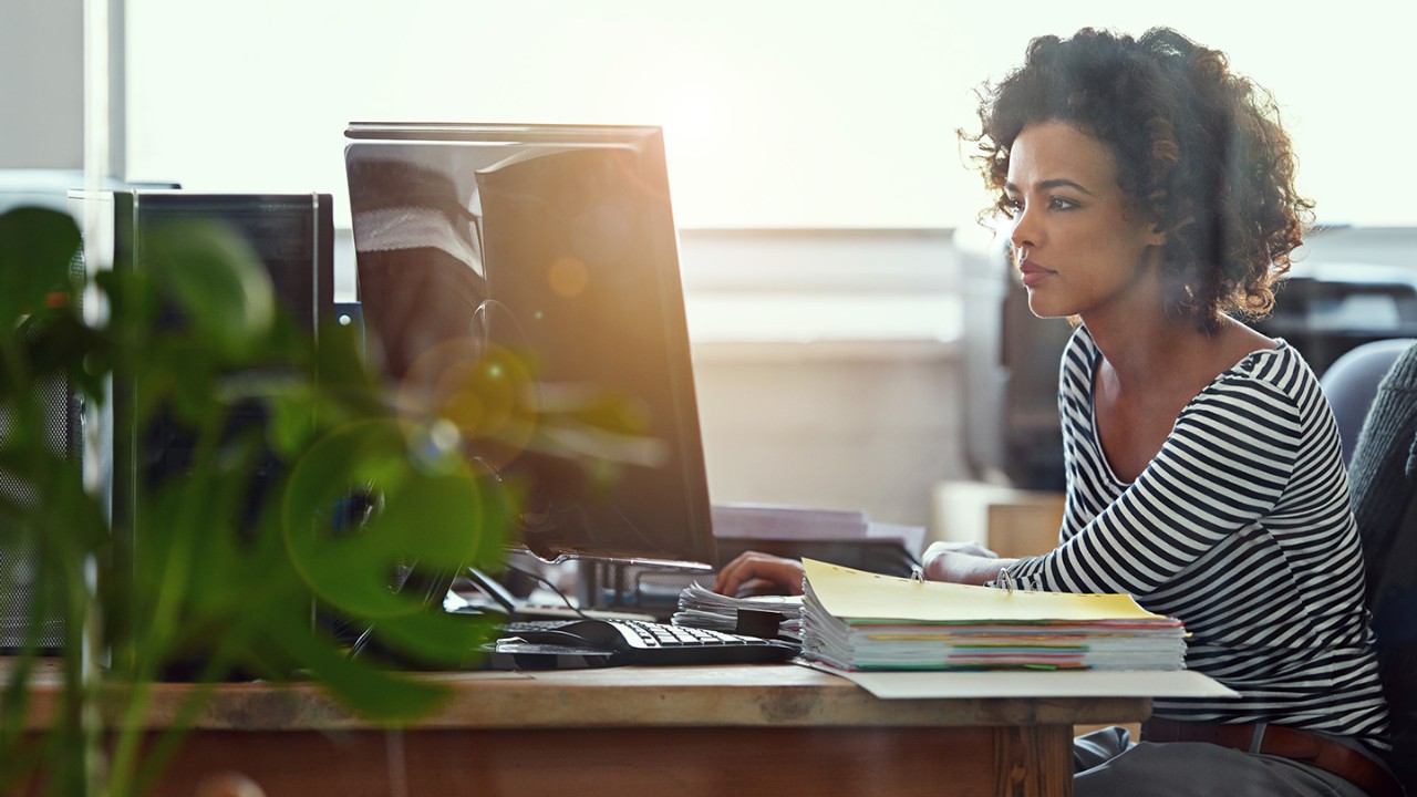 Woman sitting at desk looking at a computer monitor.