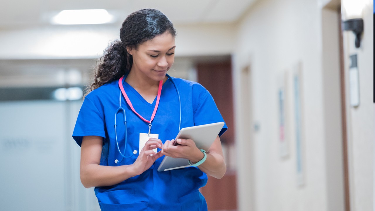 Woman healthcare professional walking with an iPad.