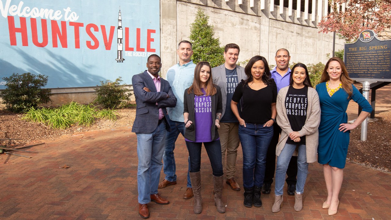 Booz Allen team standing in front of Huntsville sign