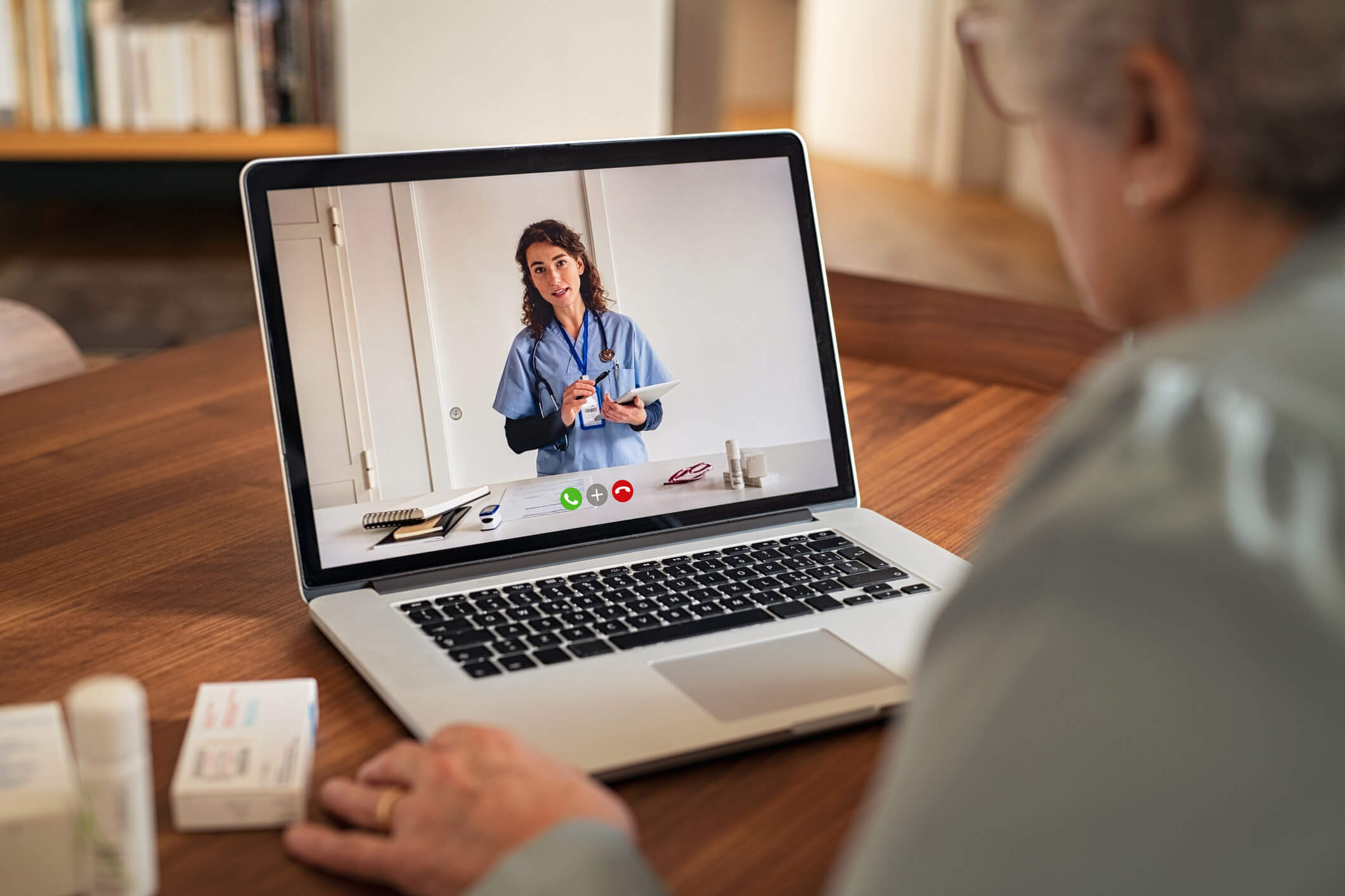 Man sitting on couch and talking with a healthcare professional on his laptop.